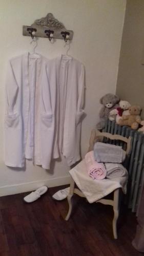 a room with a rack of white clothes and a chair at Mme Teurtroy, Chambres d'Hôtes La Prairie in Gouesnach