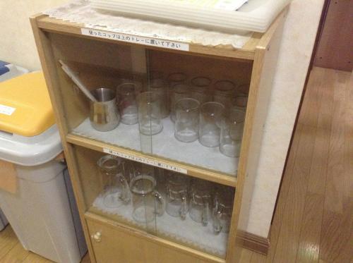 a cabinet filled with glass cups and other items at Furano Minshuku Akiba in Furano