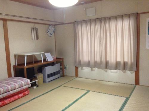 a living room with a bed and a window at Minshuku Akiba in Furano