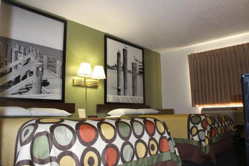 a hotel room with two beds and pictures on the walls at Super 8 by Wyndham Newport News/Jefferson Ave. in Newport News