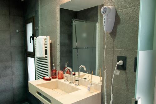 y baño con lavabo y ducha con espejo. en La Maca Suites en Villa General Belgrano