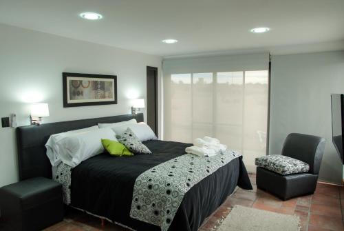 1 dormitorio con 1 cama con manta negra y silla en La Maca Suites en Villa General Belgrano