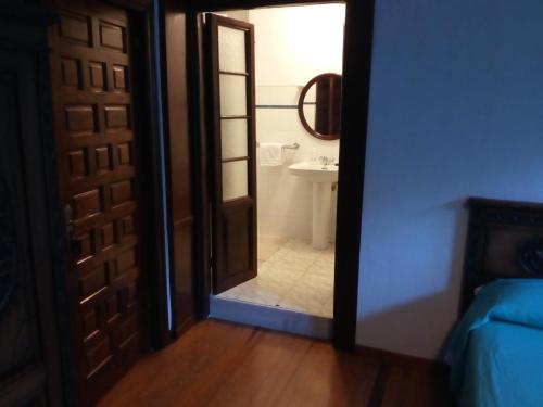 a door leading to a bathroom with a sink at Hotel Rural La Lastra in Caso