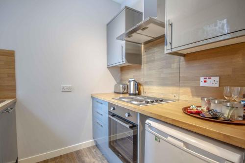 a kitchen with white cabinets and a wooden counter top at Stirling Central Apartment in Stirling