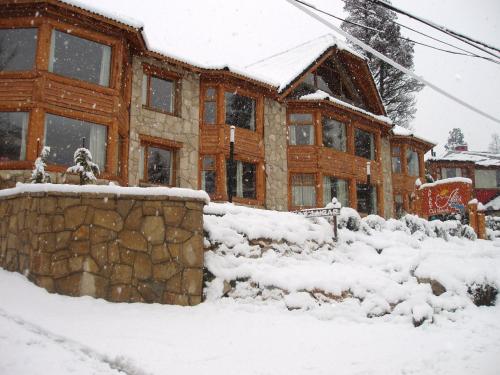 a log cabin in the snow in front at Apart Altos Del Nahuel in San Carlos de Bariloche