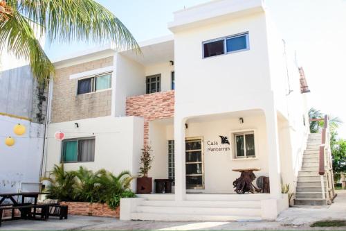 a white building with a palm tree in front of it at Casa mantarraya in Isla Mujeres