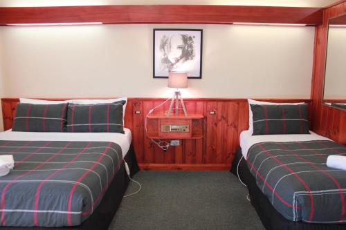a hotel room with two beds and a television at Village Family Motor Inn in Launceston