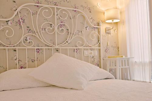 a bed with a white headboard with flowers on the wall at Balenax Pensión in Gijón