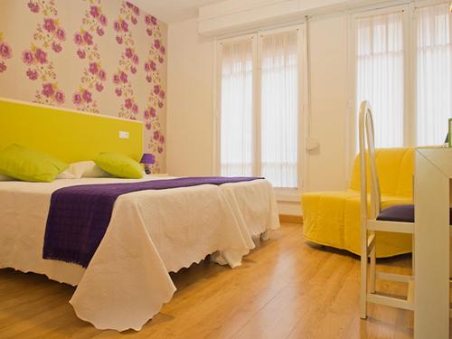 a bedroom with a bed and a yellow and purple blanket at Balenax Pensión in Gijón