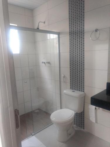 a bathroom with a toilet and a glass shower at Hotel farol de Minas in Alpinópolis