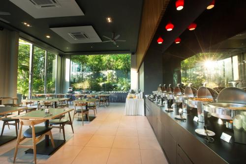 a restaurant with tables and chairs and large windows at The Haven All Suite Resort, Ipoh in Ipoh