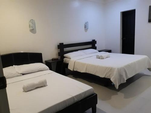 1 dormitorio con 2 camas con sábanas blancas en DaHome Pension en Vigan