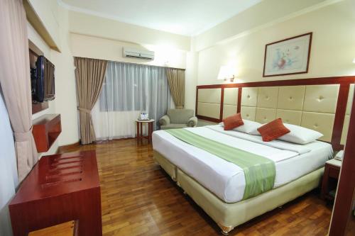 a hotel room with a large bed and a desk at Grand Menteng Hotel in Jakarta