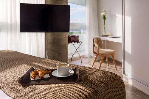 a bed with a plate of croissants and a cup of coffee at Dazzler by Wyndham Colonia in Colonia del Sacramento