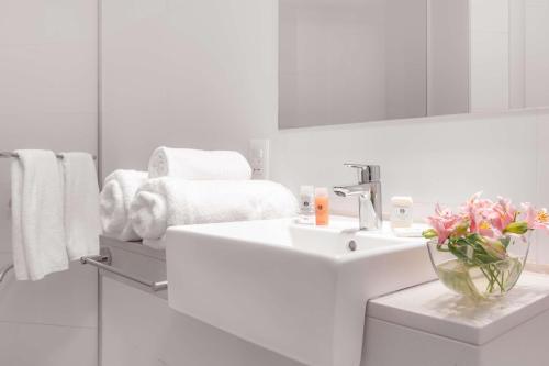 a white bathroom with a sink and a mirror at Dazzler by Wyndham Colonia in Colonia del Sacramento