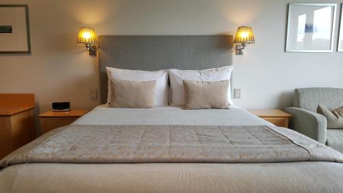 a bedroom with a large bed and a chair at Bluestone On George in Dunedin