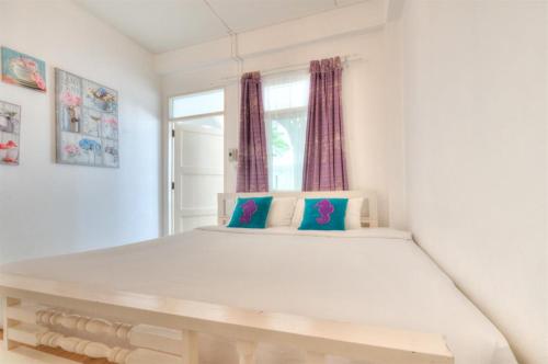 a bedroom with a large white bed with blue pillows at Khao Tao Beach Lodge Old Siam in Hua Hin