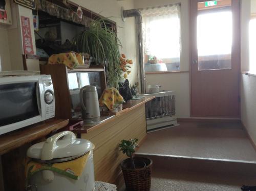 a room with a tv and a counter with a microwave at Minshuku Mutsukari in Furano