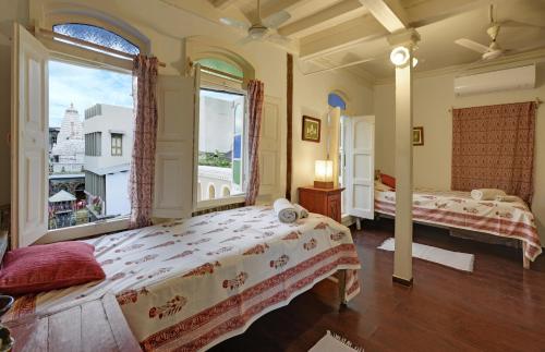 a bedroom with two beds and a large window at French Haveli in Ahmedabad