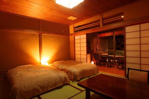 a bedroom with two beds and a table and a dining room at Amagiso in Kawazu