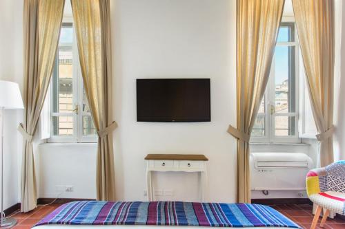 ローマにあるAndreasuite Trastevereのベッドルーム1室(壁にテレビ付)、窓2つが備わります。