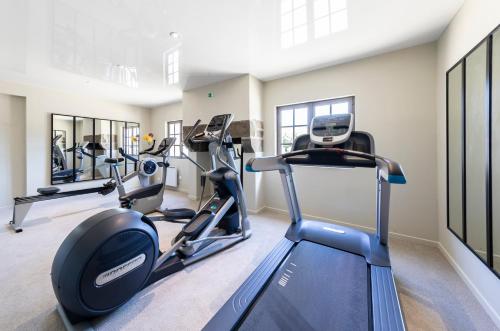a gym with treadmills and elliptical machines at Hotel de l'Abbaye; BW Premier Collection in Le Tronchet