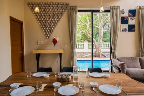 a dining room with a table and a pool at StayVista's Greenwoods Villa 10 - City-Center Villa with Private Pool, Terrace, Lift & Carrom Board in Lonavala