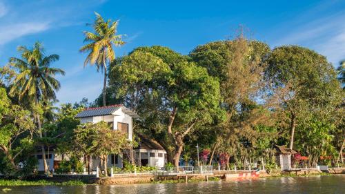 a house on the banks of a river with trees at Warmth Lake Haven in Alleppey