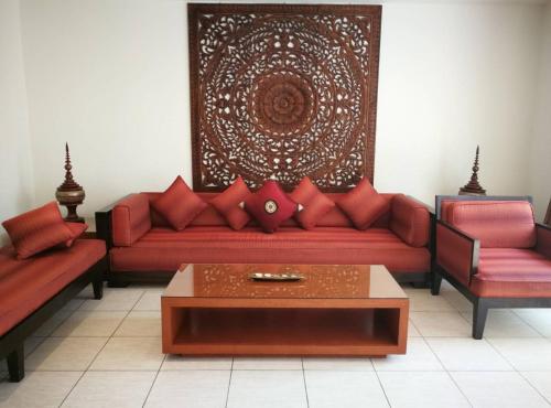 a living room with a red couch and two chairs at Hua Hin Blue Lagoon in Cha Am