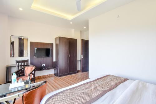 Un dormitorio con una cama y un televisor en una habitación. en Hotel Kaithli Hills Shimla, en Shimla