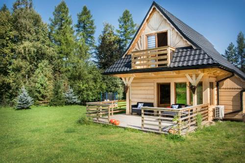 a wooden house with a porch in a field at Fiedorówka in Zakopane