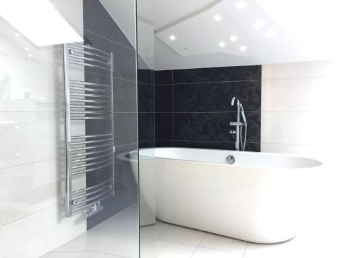 a white bath tub in a bathroom with black tiles at Stanzl Haus in Kaltenbach