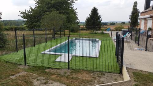 a fence with a swimming pool in a yard at Le Clos de Ramousies in Ramousies