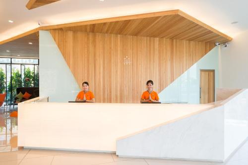 two people sitting at a counter in a lobby at J Inspired Hotel Pattaya in Pattaya
