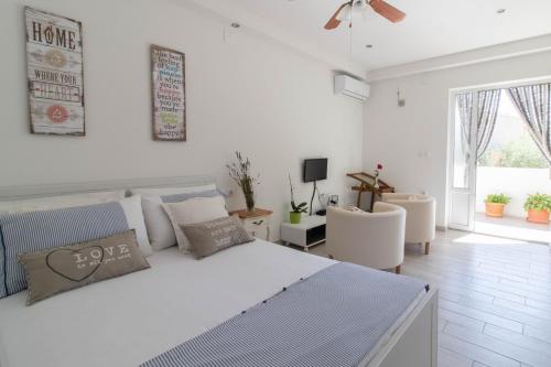 a white bedroom with a large bed and chairs at Adriana Holiday Apartment in Labin