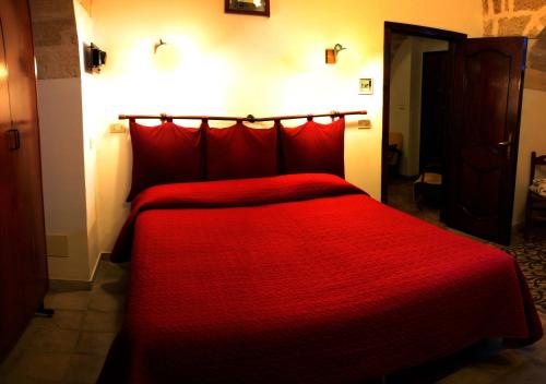 a red bed with a red comforter in a room at Masseria Sierro lo Greco in Laterza