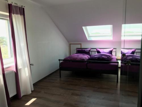 a bedroom with two beds with purple pillows and a window at Ferienwohnung Eimeldingen in Eimeldingen