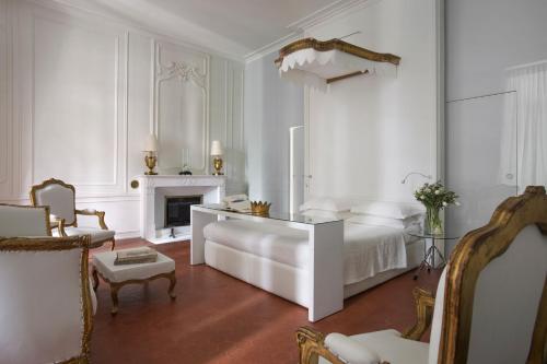 a white bedroom with a bed and a fireplace at L'Hôtel Particulier in Arles