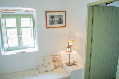 a room with a window and a table with a lamp at Perivoli House in Mylopotas