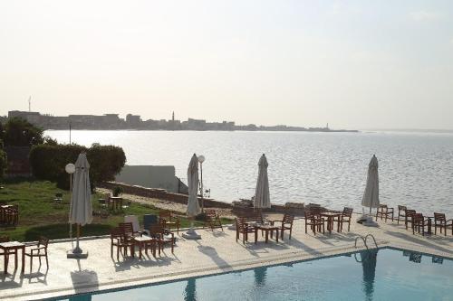 a pool with tables and umbrellas next to the water at New Panorama Resort in Fayoum Center