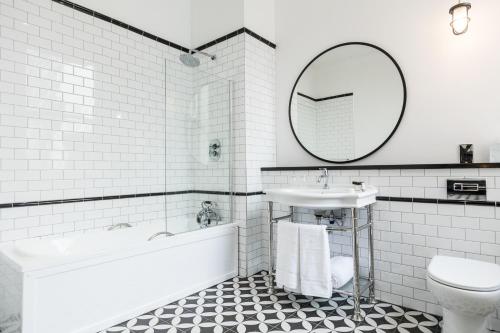 La salle de bains blanche est pourvue d'un lavabo et d'un miroir. dans l'établissement Titanic Hotel Belfast, à Belfast