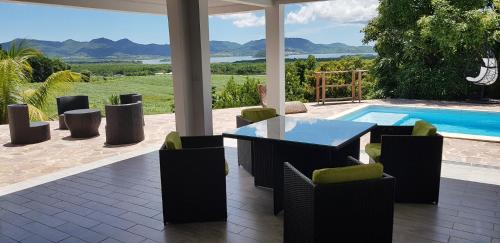 a patio with a table and chairs and a swimming pool at Résidence BelKay - Sur La Baie in Ducos