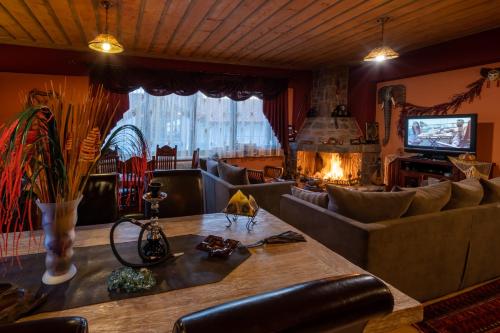 a living room with a couch and a table and a fireplace at Ξενώνας Οντάς και Spa in Arachova