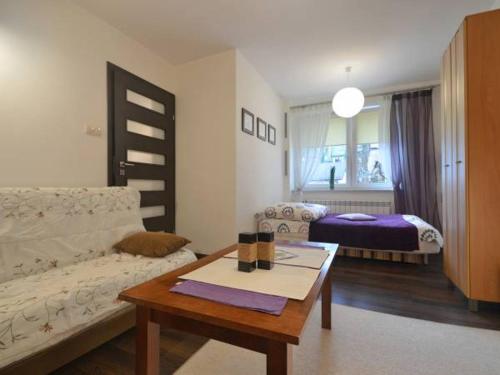 sala de estar con sofá, mesa y cama en Apartamenty Lawendowe en Krynica Zdrój