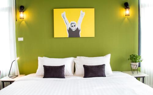 a bedroom with a white bed with a green wall at The Rodman Hotel in Chiang Mai