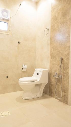 a bathroom with a toilet and a shower at Janan Al Nakheel Serviced Apartments in Al Muzāḩimīyah