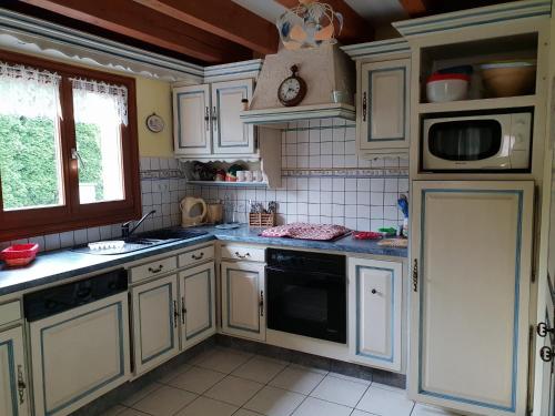 uma cozinha com armários brancos e um aparelho preto em châlet em Ferdrupt