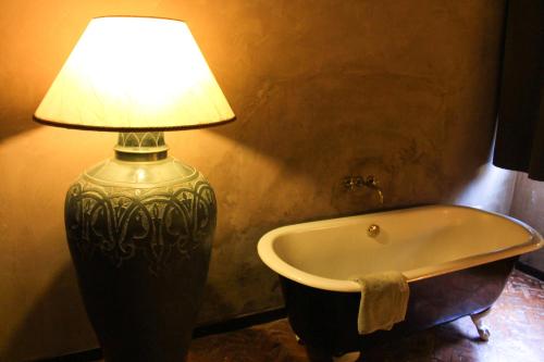 a lamp sitting next to a bath tub in a bathroom at Masseria & Spa LuciaGiovanni in Lecce