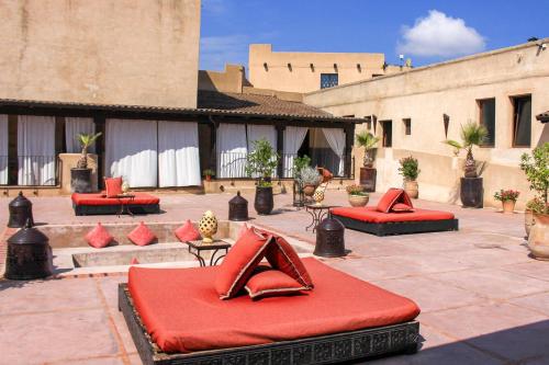 a patio with red pillows and tables and buildings at Masseria & Spa LuciaGiovanni in Lecce