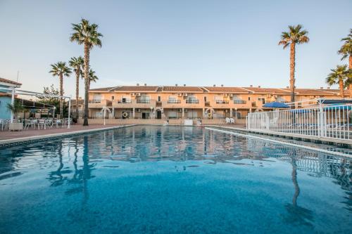 una gran piscina con palmeras y un edificio en Destino De Sol De Los Alcazares, en Los Alcázares